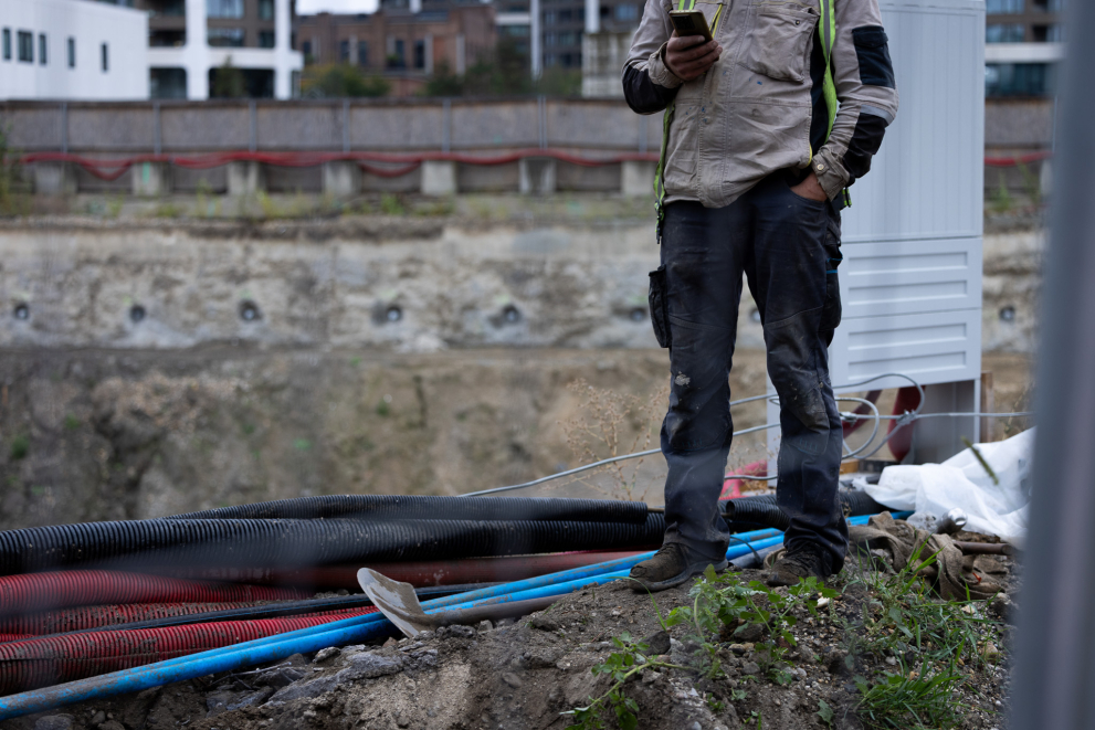 Construction worker at an active building site with scaffolding and concrete structures in the background